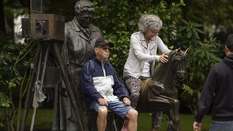 Unos turistas se hacen fotos sentados en la estatua de La Torera en Oviedo