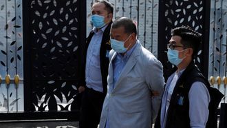 El empresario Jimmy Lai Chee-ying es conducido por dos agentes tras su detenci&oacute;n.