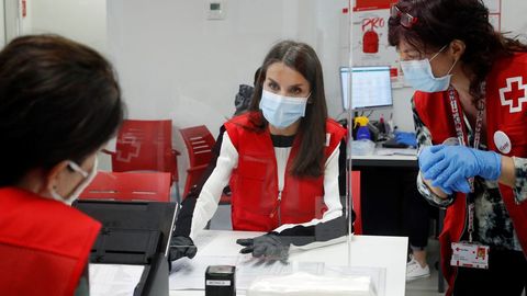 La reina Letizia (c) visita, este lunes, una de las sedes de Cruz Roja en Madrid, para conocer de primera mano la labor que desarrollan esta entidad y sus voluntarios durante la emergencia sanitaria, entre ellas, el apoyo a las personas mayores.