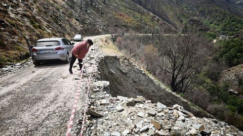 Una vecina se asoma al barranco sobre el que se apoya la carretera que comunica todas estas aldeas en uno de los tramos deteriorados