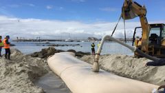 Trabajos de instalaci�n de tubos geotextiles en la playa de Carabuxeira, en Sanxenxo