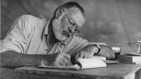 Ernest Hemingway escribiendo durante un campamento en Kenia.