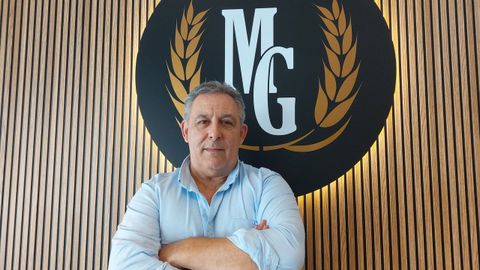 Miguel Giz, de 58 a�os, junto al logotipo de la marca que lleva sus iniciales, en la cafeter�a-pasteler�a que gestiona en Ortigueira, el antiguo Dolan