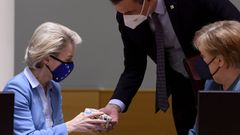 El presidente espa�ol, Pedro S�nchez, le regala unos patucos para su primer nieto a la presidenta de la Comisi�n, Ursula Von der Leyen, ante la mirada de Angela Merkel