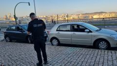 Un agente de la Polica Nacional delante de dos de los vehculos que aparecieron en la zona de la Domus con las ventanillas rotas
