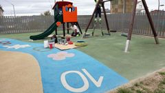 Un operario municipal trabajando en el pintado de los columpios del colegio