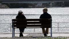 Una pareja de jubilados descansan en un banco en Viveiro