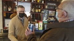 Un cliente muestra su certificado al hostelero Emilio V�zquez en el caf� Avenida de la plaza de Espa�a