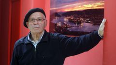 Rafael Pillado posando ante una fotografa de la ra de Ferrol y los astilleros