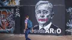 Un hombre observa un mural de uribe en Bogot