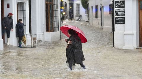 Una vecina de Grazalema camina por una calle inundada debido a las intensas lluvias que se registran este mi�rcoles en la localidad gaditana