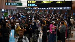 Multitud de viajeros esperan en la cola del aeropuerto internacional Soekarno-Hatta, en Yakarta.