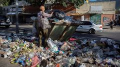 Un hombre busca en la basura en una calle de Caracas