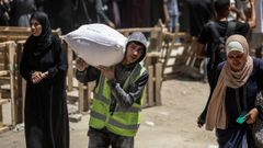 Palestinos llevan bolsas de harina mientras otros esperan frente a un punto de distribuci�n establecido por el Programa Mundial de Alimentos (PMA) de las Naciones Unidas en la ciudad de Gaza.