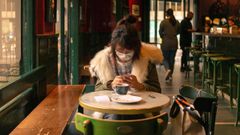 Una mujer toma un cafe en un bar del centro de Barcelona