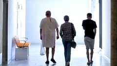 Un paciente en pijama de hospital paseando por el pasillo con su familia