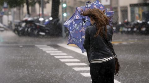 Una mujer intenta protegerse de la lluvia en el centro de Barcelona