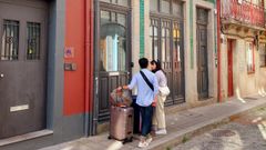 Dos turistas con sus maletas, a la entrada de una vivienda turstica en Oporto.
