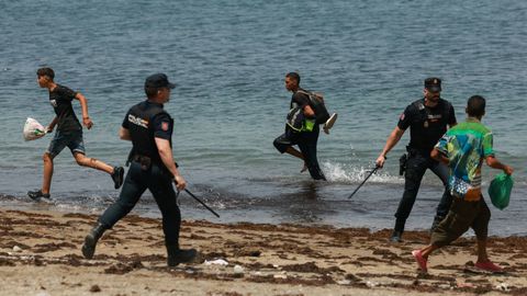 Polic&iacute;as nacionales tratan de controlar a un grupo de inmigrantes en la costa de Ceuta.