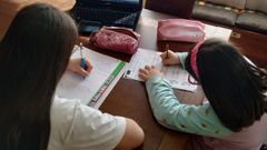 Lucía, alumna de Secundaria,  y Lola, de Primaria, hacen tareas escolares en el comedor de su casa