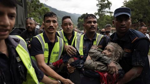 Agentes de polic�a trasladan a una superviviente a una zona segura tras la riada en Trishuli