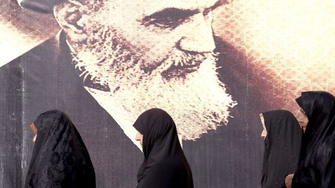 Un grupo de mujeres pasan delante de un mural con el rostro del ayatol Jomeini en Tehern