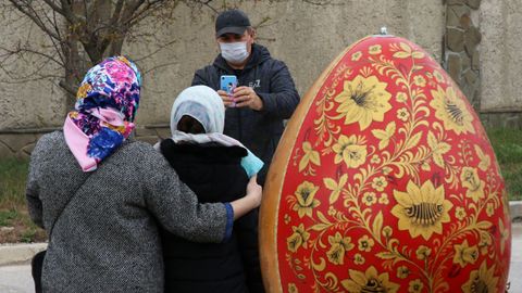 Un hombre le saca una foto a una mujer despus de una ceremonia para bendecir los pasteles y los huevos de Pascua en la vspera de la Pascua ortodoxa, en Yevpatoriya, Crimea