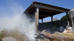 Un bombero enfr�a con agua las pacas que arden dentro del almac�n