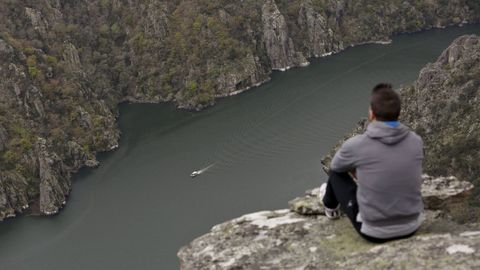 Un turista en el mirador de Cividade, en Sober, mientras uno de los catamaranes recorre el Ca��n del Sil