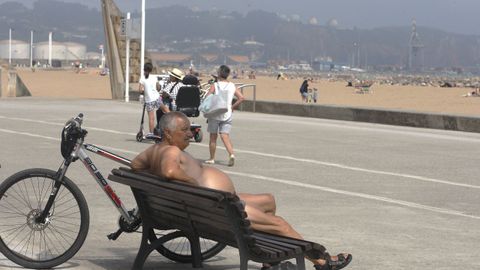 Un hombre descansa frente a la playa de Poniente, en Gij�n