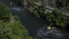 Dos helic�pteros de lucha contra los incendios cargan agua en el r�o Sil, en Nogueira de Ramu�n, para tratar de extinguir el fuego en Pant�n y Sober.