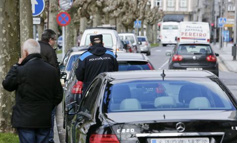 Un agente sanciona a un veh�culo mal aparcado ayer al mediod�a en Ram�n Ferreiro. 