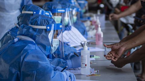 En Kuala Lumpur, los trabajadores llevan trajes de protección durante un trámite administrativo