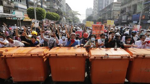 Los manifestantes detr�s de una barrera de contenedores mientras se enfrentan a la polic�a antidisturbios durante una protesta en Rang�n