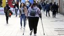 Una mujer caminando apoyada de muletas por una calle de Vigo. 