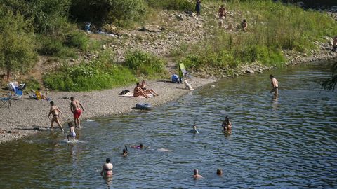 Bañistas refrescándose en el agua esta tarde en el río Trubia