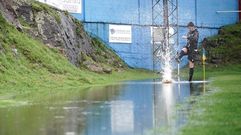 Un jugador del Compos comprueba el estado del terreno de juego antes de suspenderse el partido de Cambados.