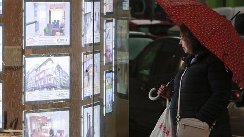 Una mujer observa ofertas de pisos en el escaparate de una inmobiliaria de Lugo.