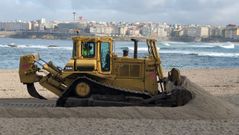 Una bulldozer, trabajando en la playa de Riazor para levantar la duna de protecci�n para los temporales