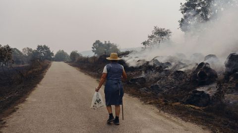 Una vecina abandonando su aldea, afectada por el fuego, en Manzaneda.