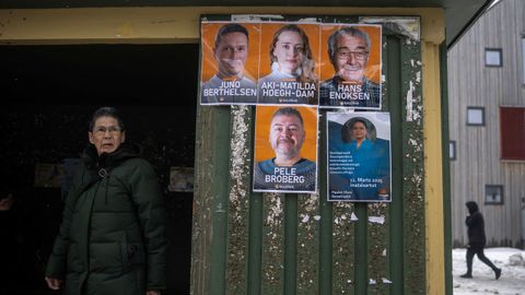 Una mujer espera en una parada del autobús con propaganda electoral en la capital de Groenlandia