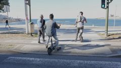 Dos patinetes cruzan un paso de peatones en el paseo mar�timo de A Coru�a