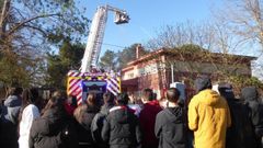 Los bomberos refrescan con agua una de las edificaciones ante la mirada de los estudiantes