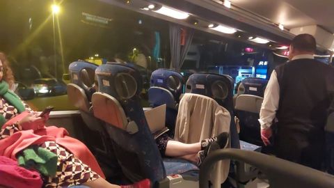 Pasajeros del vuelo Bilbao-Santiago, a la una y media de la madrugada, a la espera de noticias de Iberia en el autob�s estacionado en la gasolinera de Novellana en Cudillero.