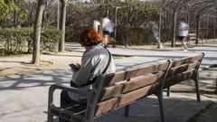 Una persona sentada en un banco en un parque de Madrid.