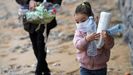 La pequea Alejandra, de 4 aos, el pasado domingo, recogiendo envases de plstico en la playa de San Lorenzo, seguida de su padre, Alexandre