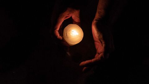 Un miembro de la organizacin Pueblos Sin Fronteras sostiene una vela durante una vigilia para concienciar sobre el acoso policial a migrantes, en Tijuana (Baja California) 