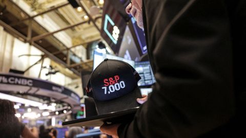 Un operador en la bolsa de Nueva York sostiene una gorra con los 7.000 puntos del S&P 500.