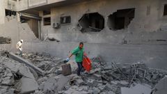 Un paramdico lleva una camilla, mientras los palestinos inspeccionan los daos en un barrio residencial, luego de una operacin israel en Ciudad de Gaza.
