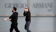 Un hombre coloc�ndose una mascarilla en Mil�n, ante el r�tulo de la marca textil